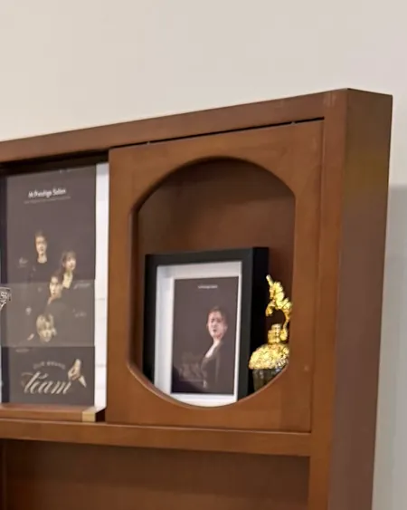 The salon's arched walnut shelf with the team poster